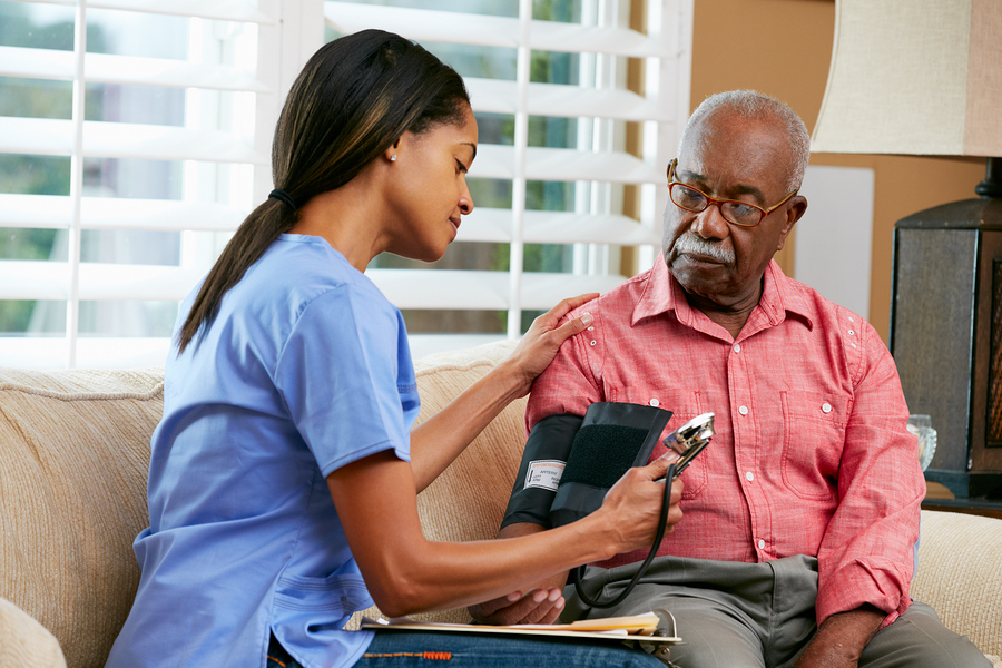 A caregiver checking a gentleman’s blood pressure at home